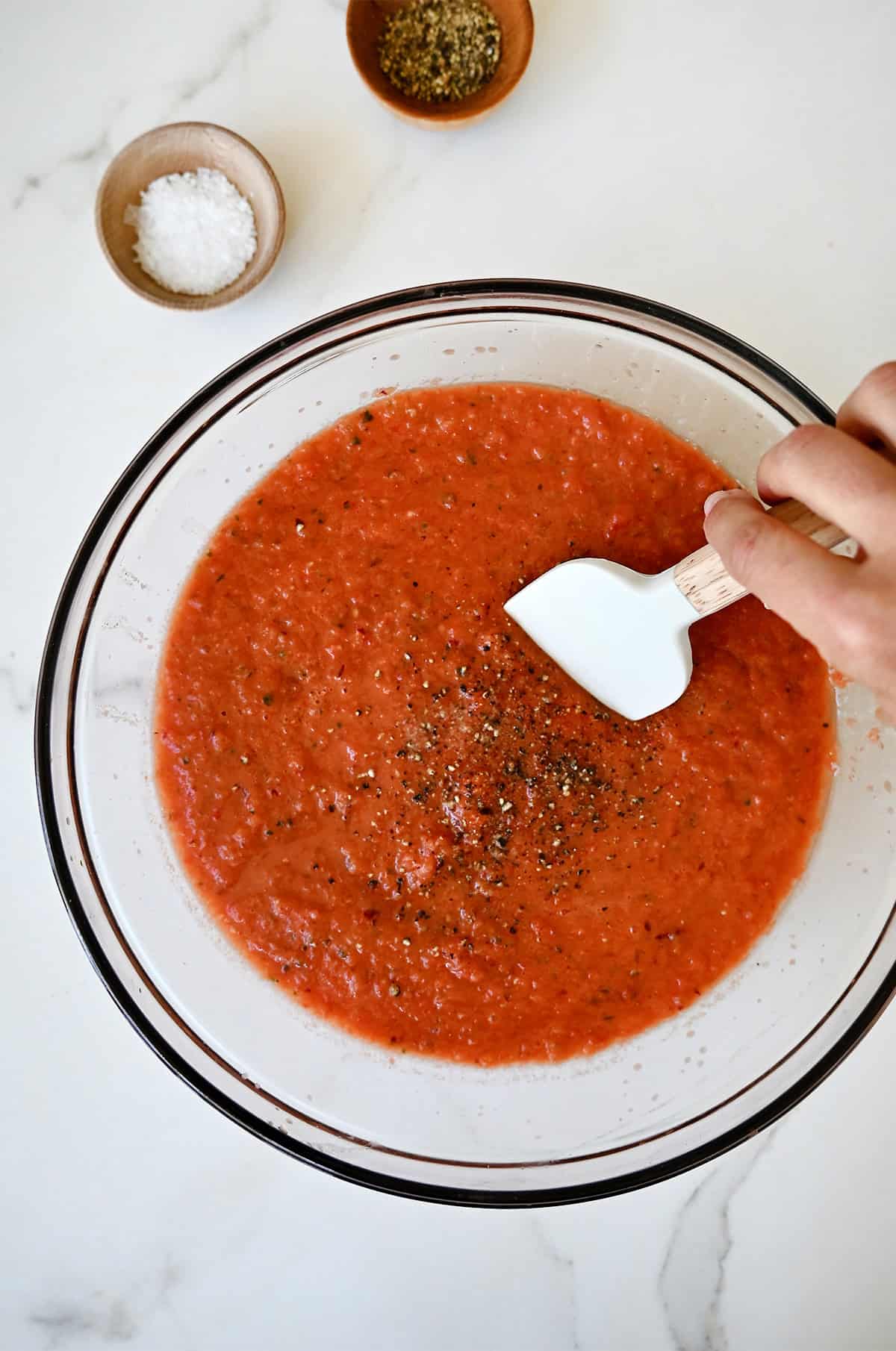 Season chilled gazpacho in a bowl with salt and pepper.