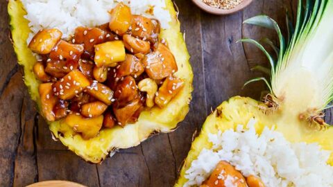 Two pineapple bowls filled with chicken and white rice