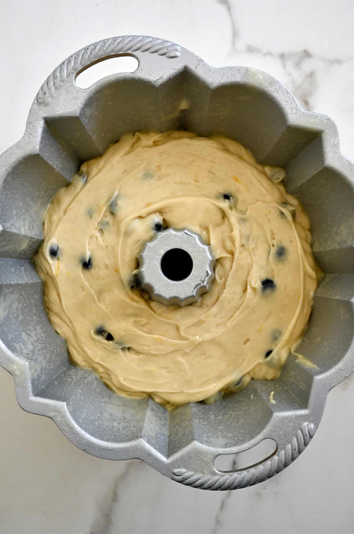 Pound cake batter with blueberries in a bundt pan.