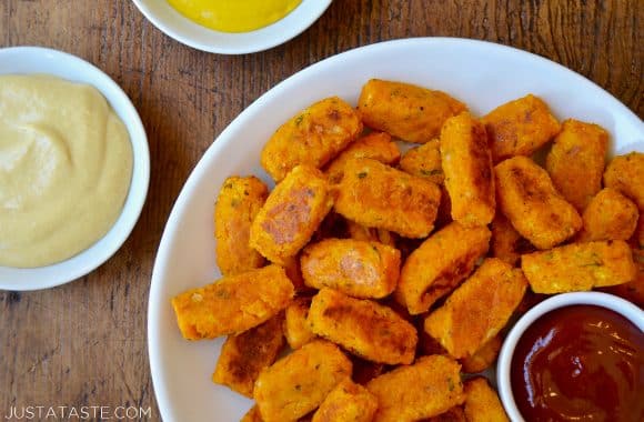 A white plate with butternut squash tots, ketchup and mustard