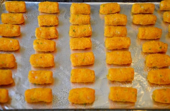 A foil-lined baking sheet with butternut squash tots 