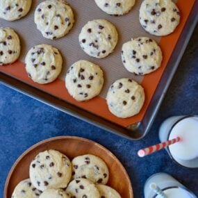 A baking sheet with Cake Mix Chocolate Chip Cookies and two glasses of milk