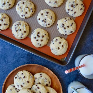 A baking sheet with Cake Mix Chocolate Chip Cookies and two glasses of milk