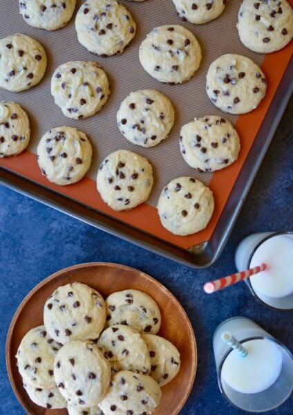A baking sheet with Cake Mix Chocolate Chip Cookies and two glasses of milk