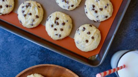 A baking sheet with Cake Mix Chocolate Chip Cookies and two glasses of milk