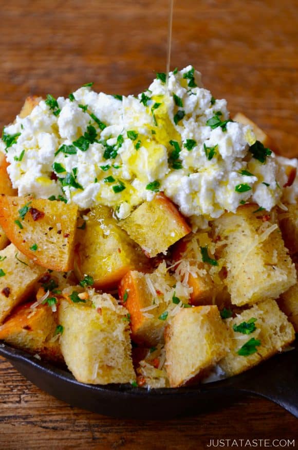 A skillet filled with cheesy garlic bread topped with ricotta cheese