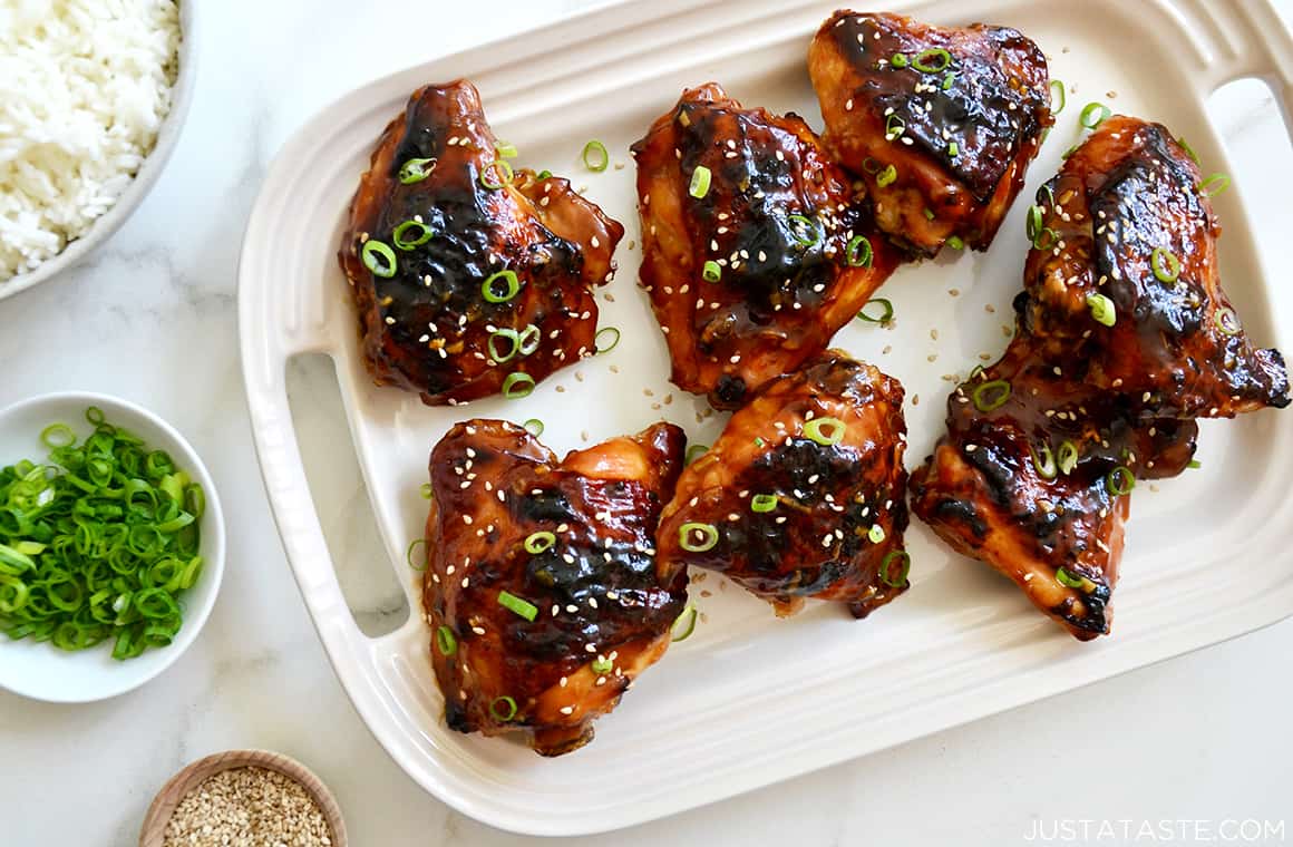 Glazed Honey Soy Chicken Thighs on a serving plate garnished with sesame seeds and sliced scallions