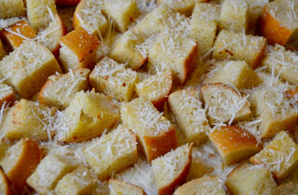 Cubes of garlic bread with Parmesan cheese on a baking sheet 