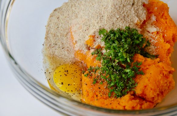 A glass bowl containing pureed butternut squash, onions, egg, breadcrumbs and sage