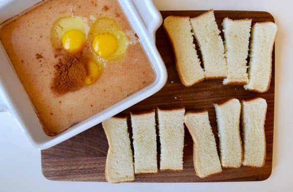 Texas toast cut into sticks alongside a dish of eggs and milk