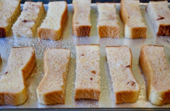 French toast sticks arranged on a foil-lined baking sheet