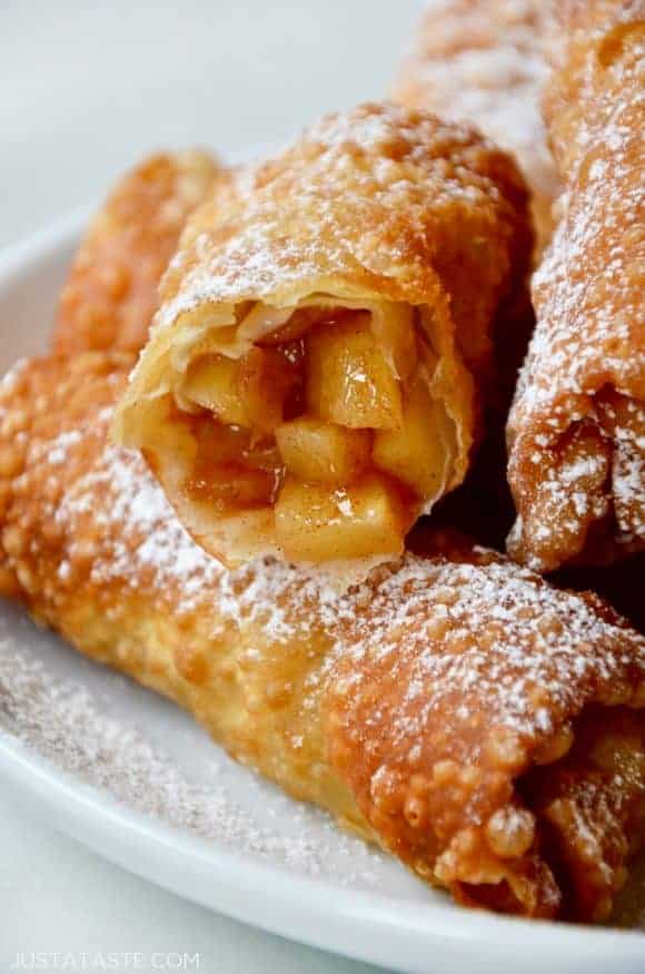 Apple pie egg rolls on a white plate with one cut open