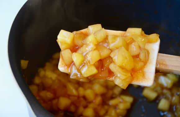 Apple pie mixture on a spatula and in a sauce pan