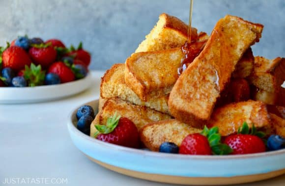 Baked French toast sticks and fruit on plates with maple syrup