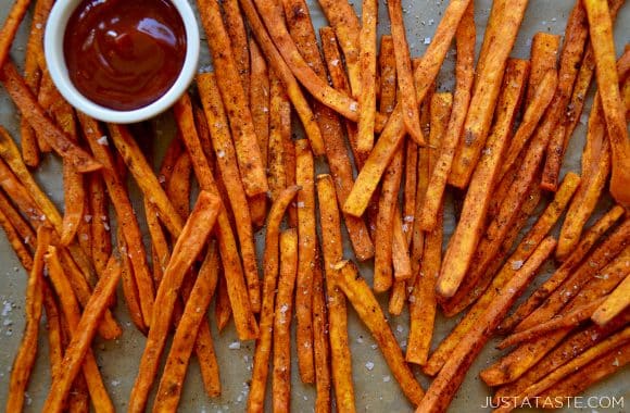 Sweet potato fries scattered on a baking sheet