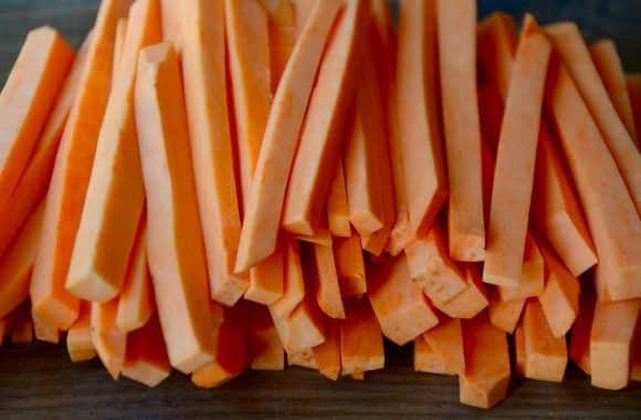 Cut, raw sweet potatoes on a wood cutting board