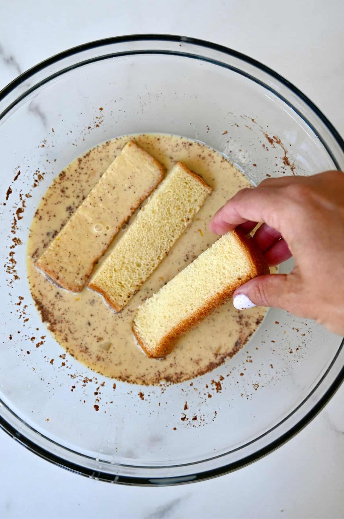 Dipping bread batons in vanilla custard to make French toast.