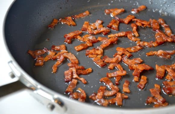 Bacon pieces cooking in a nonstick pan