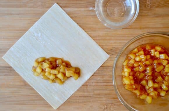 Egg roll wrappers and apple pie filling on a wood cutting board