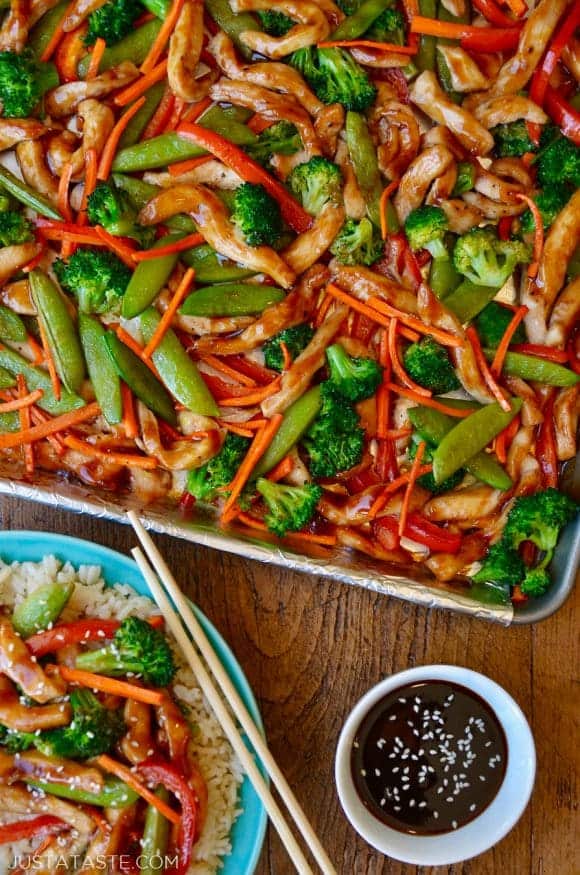 A sheet pan with chicken teriyaki and vegetable next to a plate