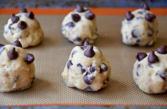 Mounds of chocolate chip cookie dough spaced out on a baking sheet