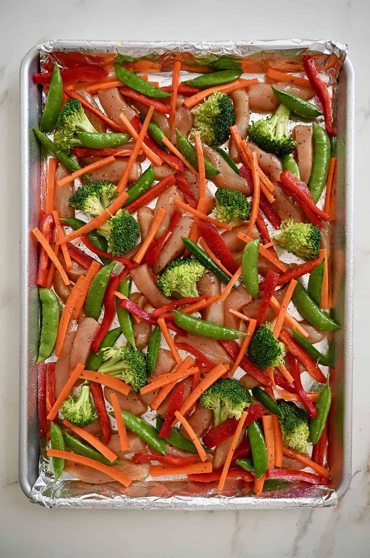 Unbaked chicken teriyaki on a foil-lined sheet pan before baking.
