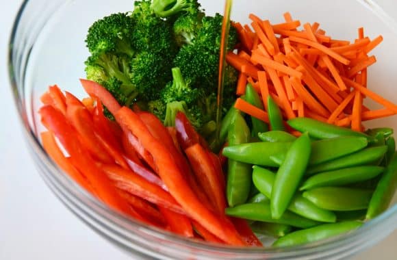 Cut vegetables in a glass bowl with teriyaki sauce on top