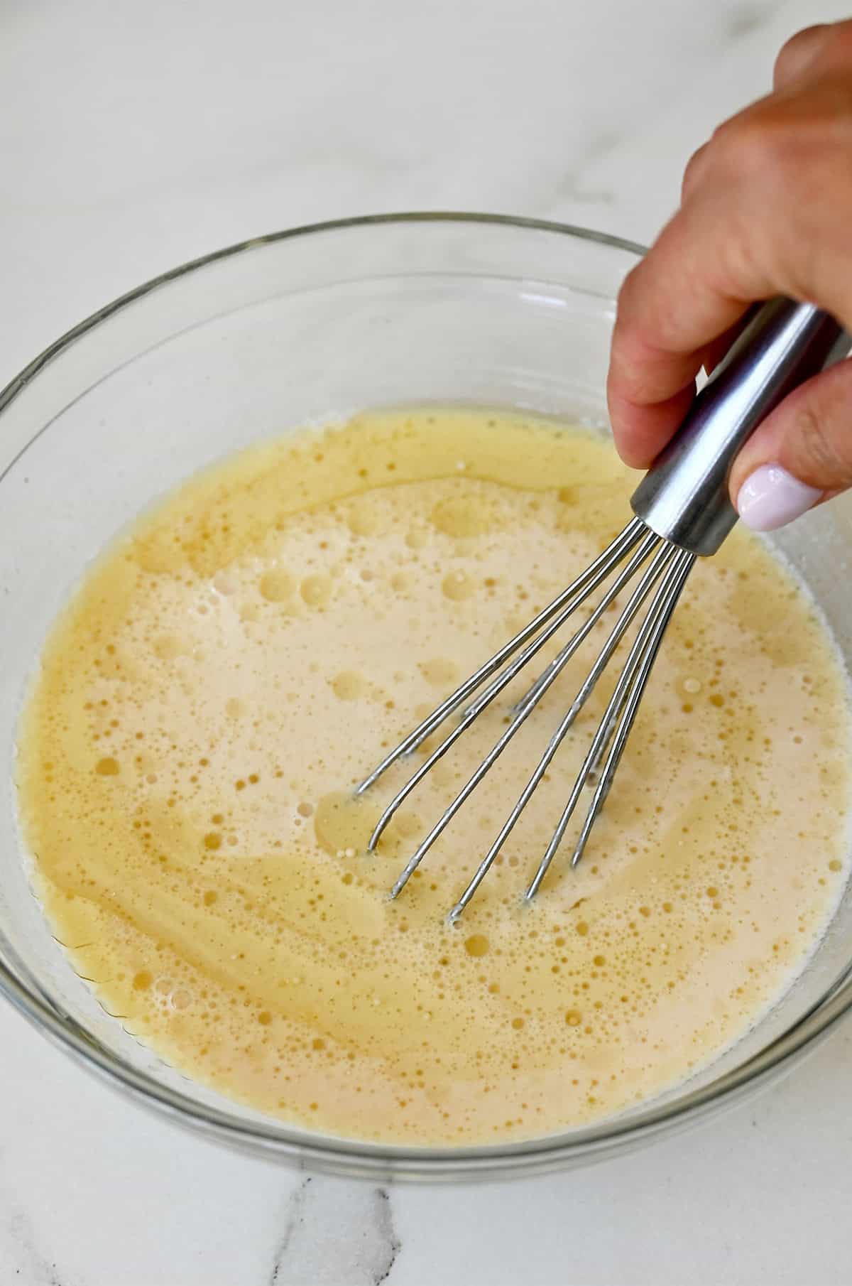 Whisking applesauce with milk, egg, oil and vanilla for pancakes.
