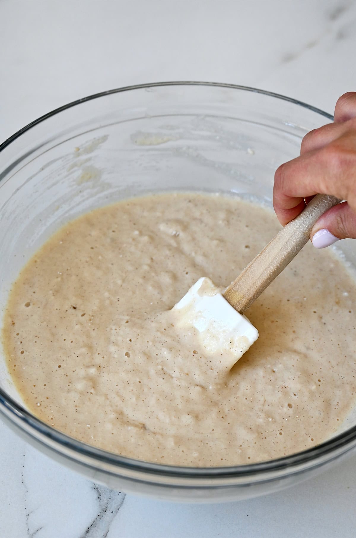 Lumpy applesauce pancake batter in a glass bowl.