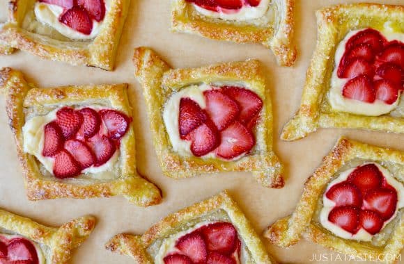 Puff pastry Danishes with cream cheese and strawberries on tan parchment paper