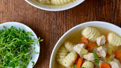 Gnocchi chicken soup in two bowls with a bowl of fresh thyme