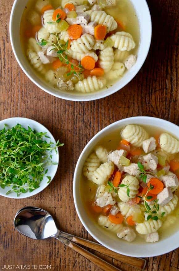 Gnocchi chicken soup in two bowls with a bowl of fresh thyme