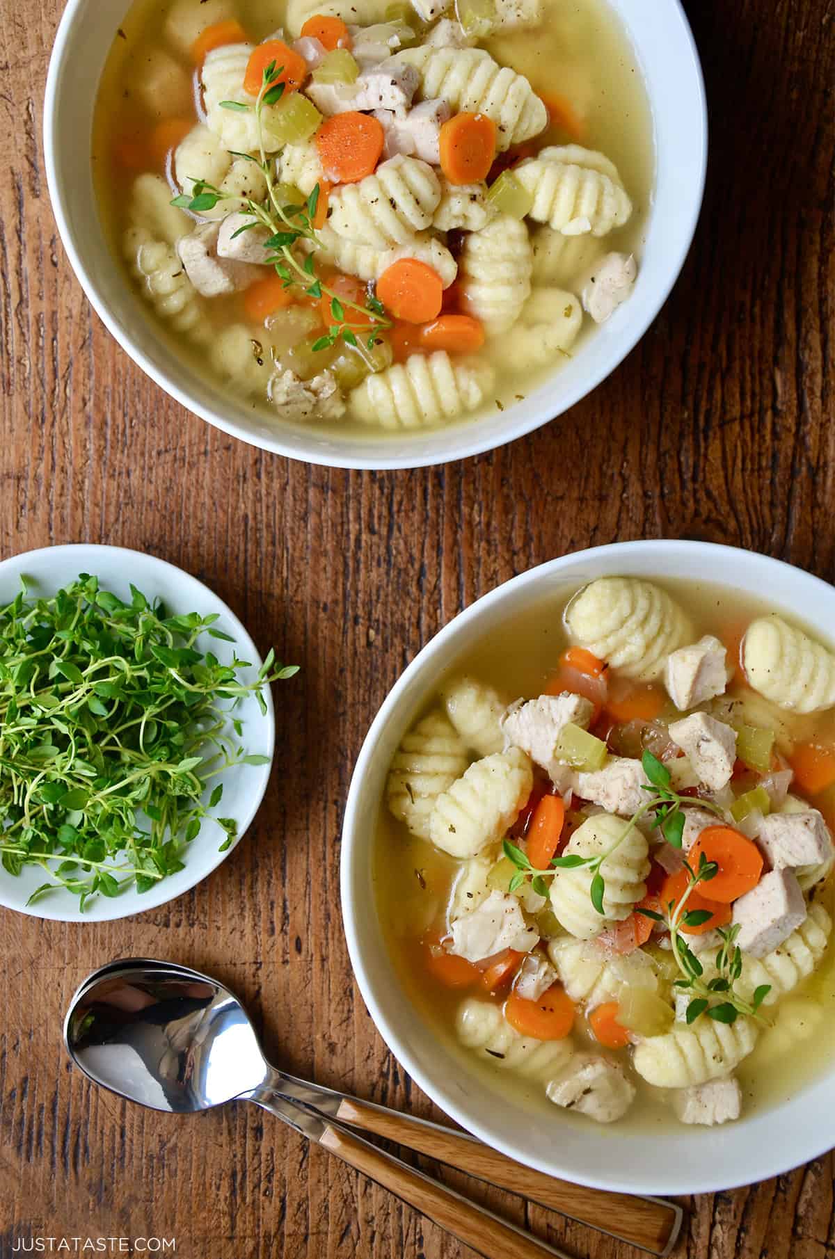 Two bowls containing chicken gnocchi soup garnished with microgreens.