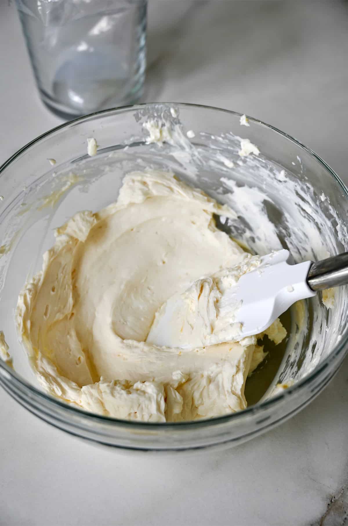 Lemon cream cheese in a glass bowl with a spatula.