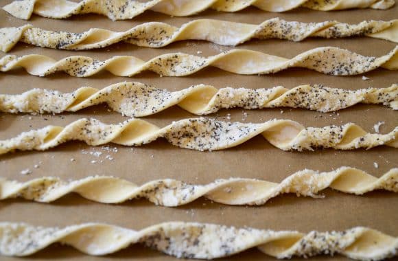 Unbaked puff pastry cheese straws arranged on a baking sheet