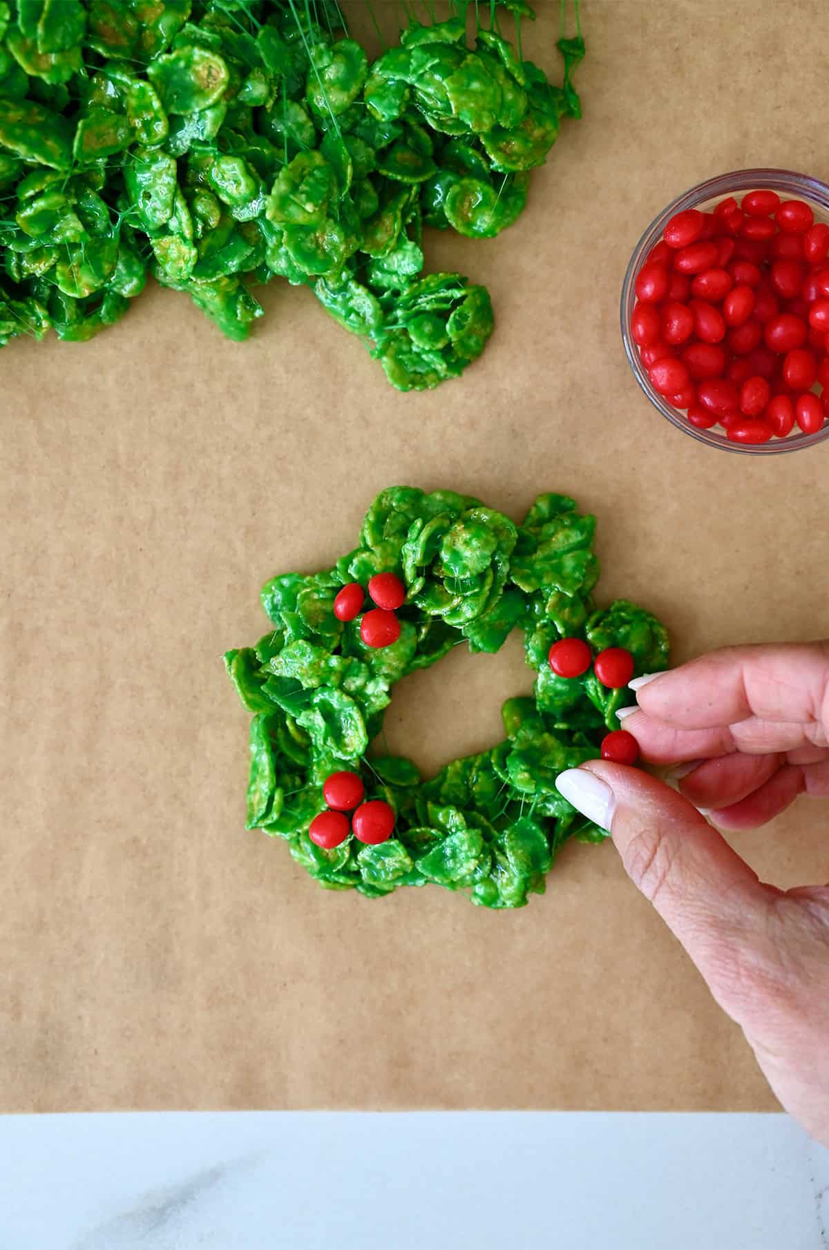 Add Red Hot candies to green cornflake wreath cookies.