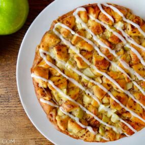 A white plate with Apple Cinnamon Roll Bake topped with icing