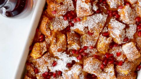 A white baking dish with pumpkin French toast topped with pomegranate arils