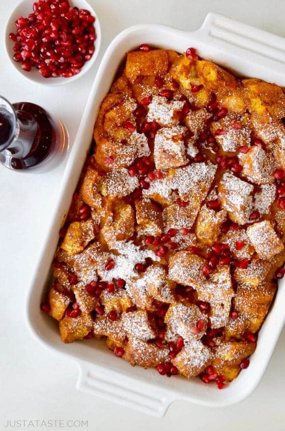 A white baking dish with pumpkin French toast topped with pomegranate arils