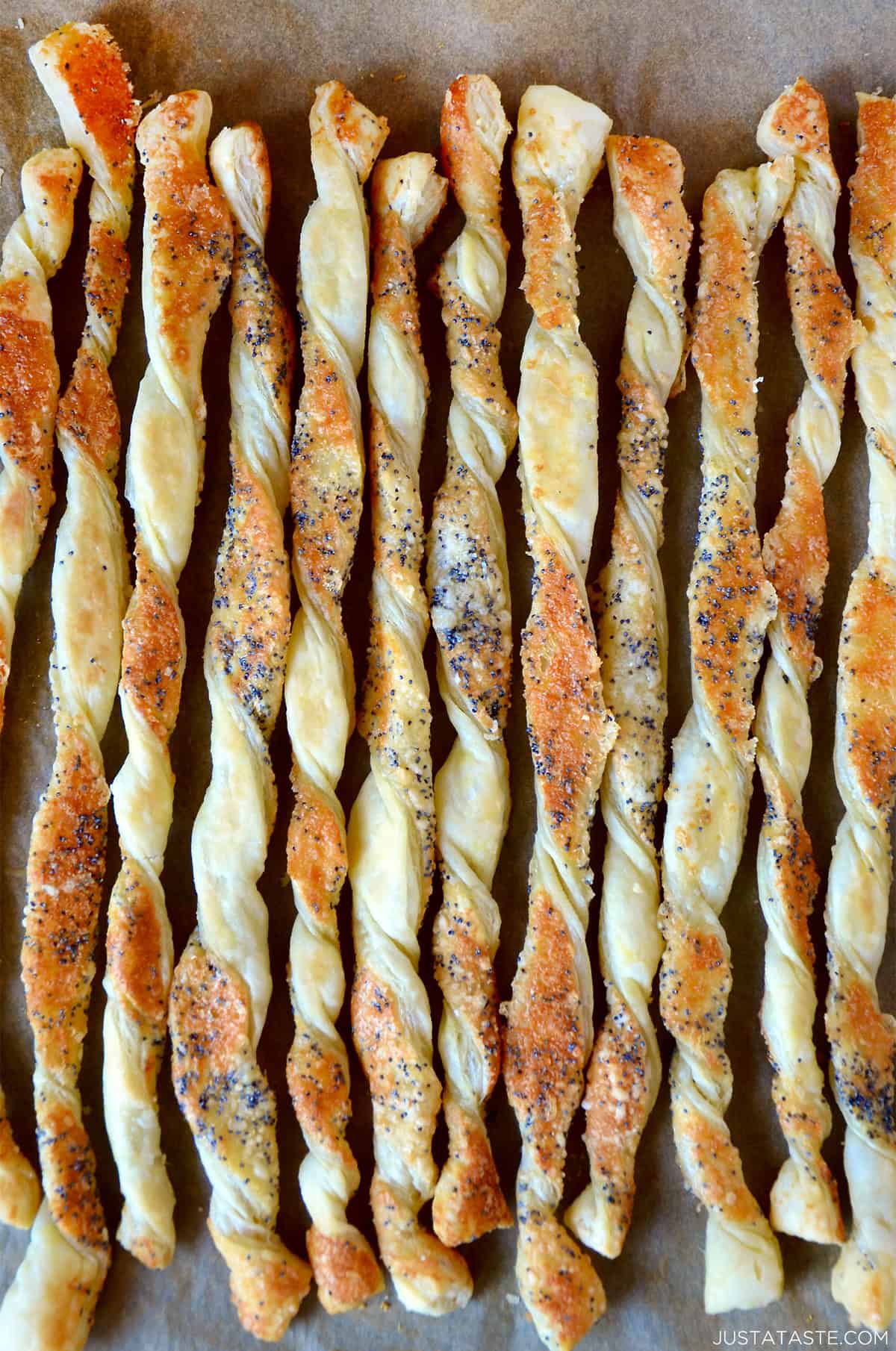 Cheesy puff pastry twists on a baking sheet lined with parchment paper.