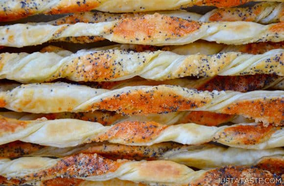 A close-up of baked cheese straws with poppy seeds