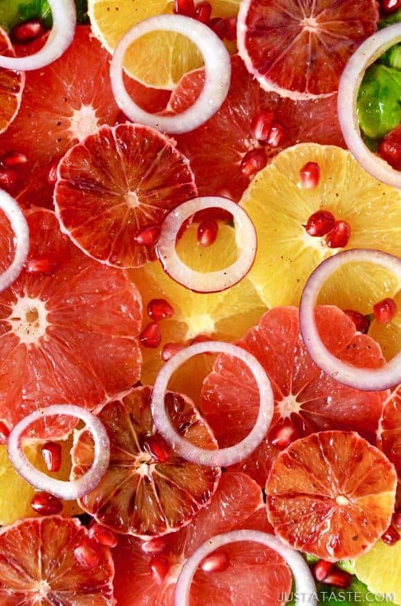 A close up of citrus salad with red onions and pomegranate arils