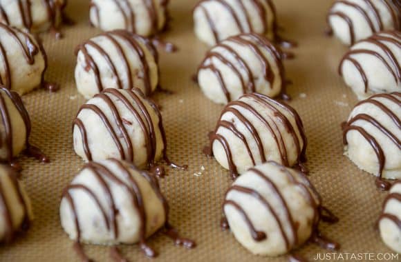 A baking sheet containing Easy Pecan Balls drizzled with chocolate