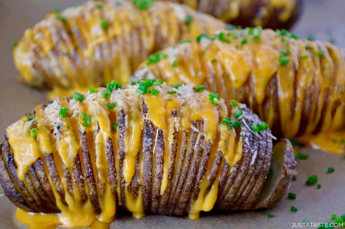 Hasselback potatoes with cheddar and Parmesan cheeses, and garnished with fresh herbs.