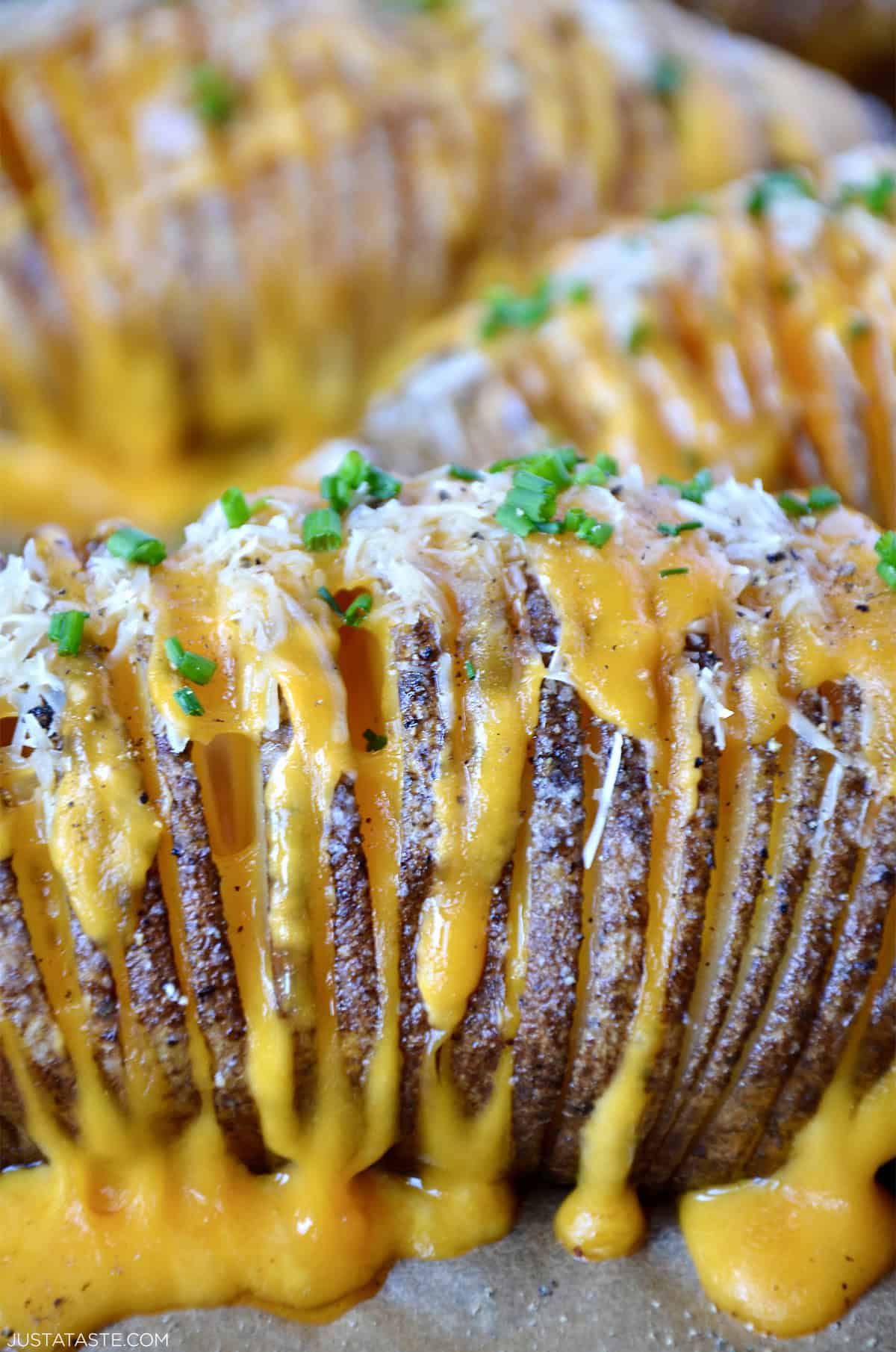 Close-up of cheesy hasselback potatoes with melted cheddar, parmesan and fresh chives.