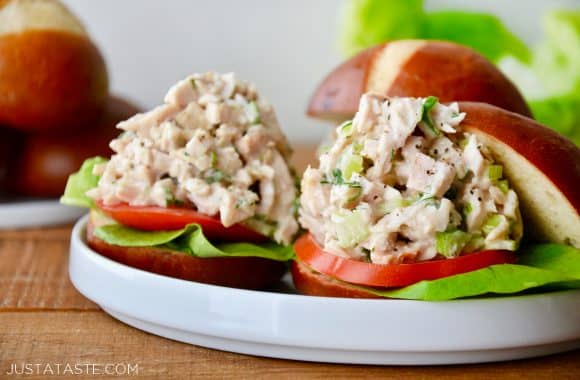 A white plate with Leftover Turkey Sliders on pretzel buns with lettuce and tomato