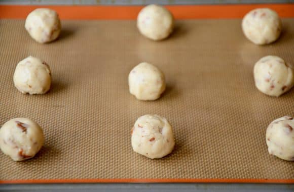 A baking sheet with balls of pecan cookie dough