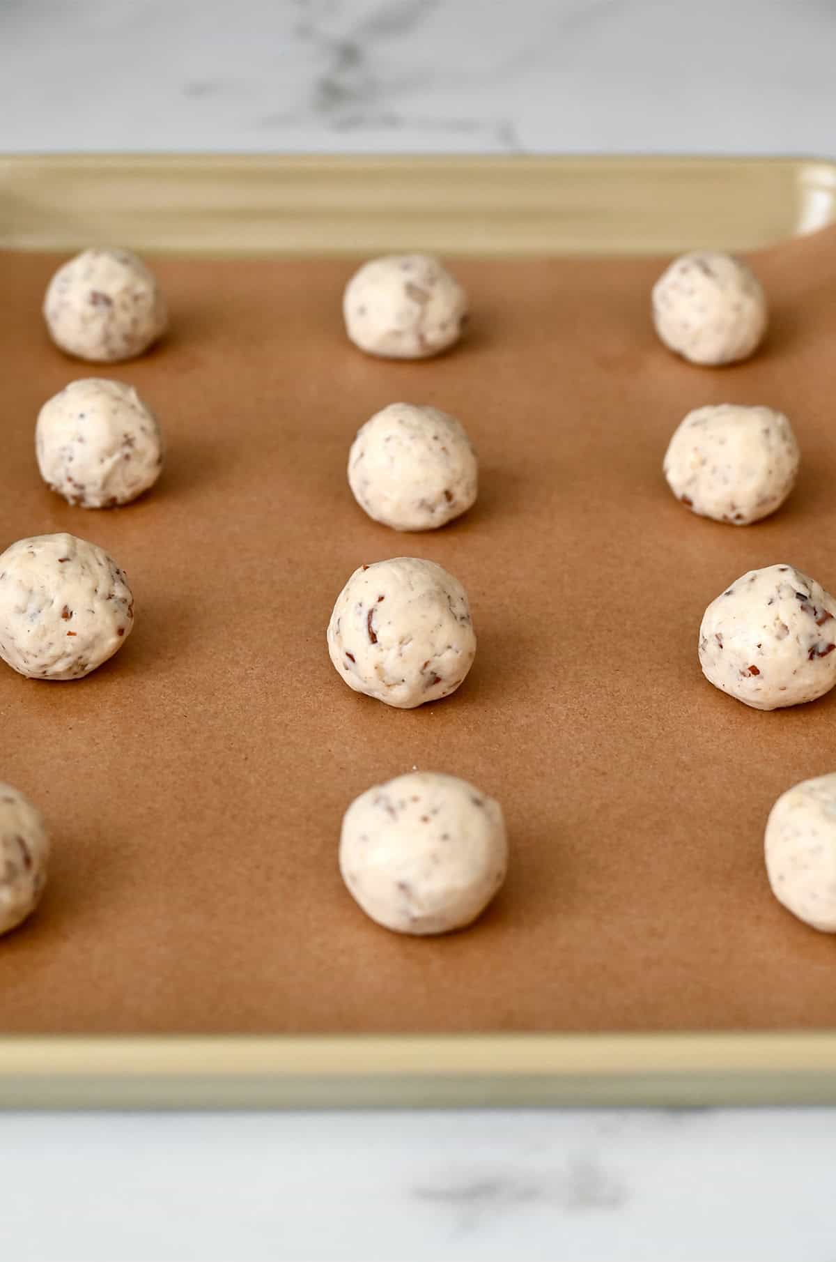 Pecan snowball cookie dough balls on a parchment paper-lined baking sheet.