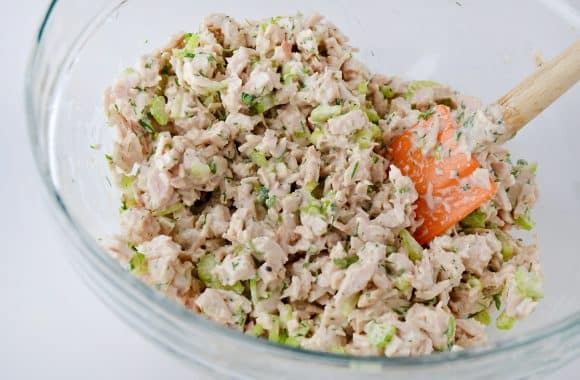 A clear bowl containing Leftover Turkey Salad and an orange spatula