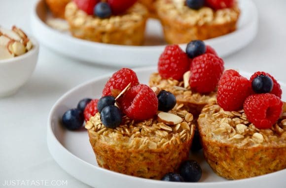 Baked Oatmeal Cups on white plate topped with fresh raspberries and blueberries